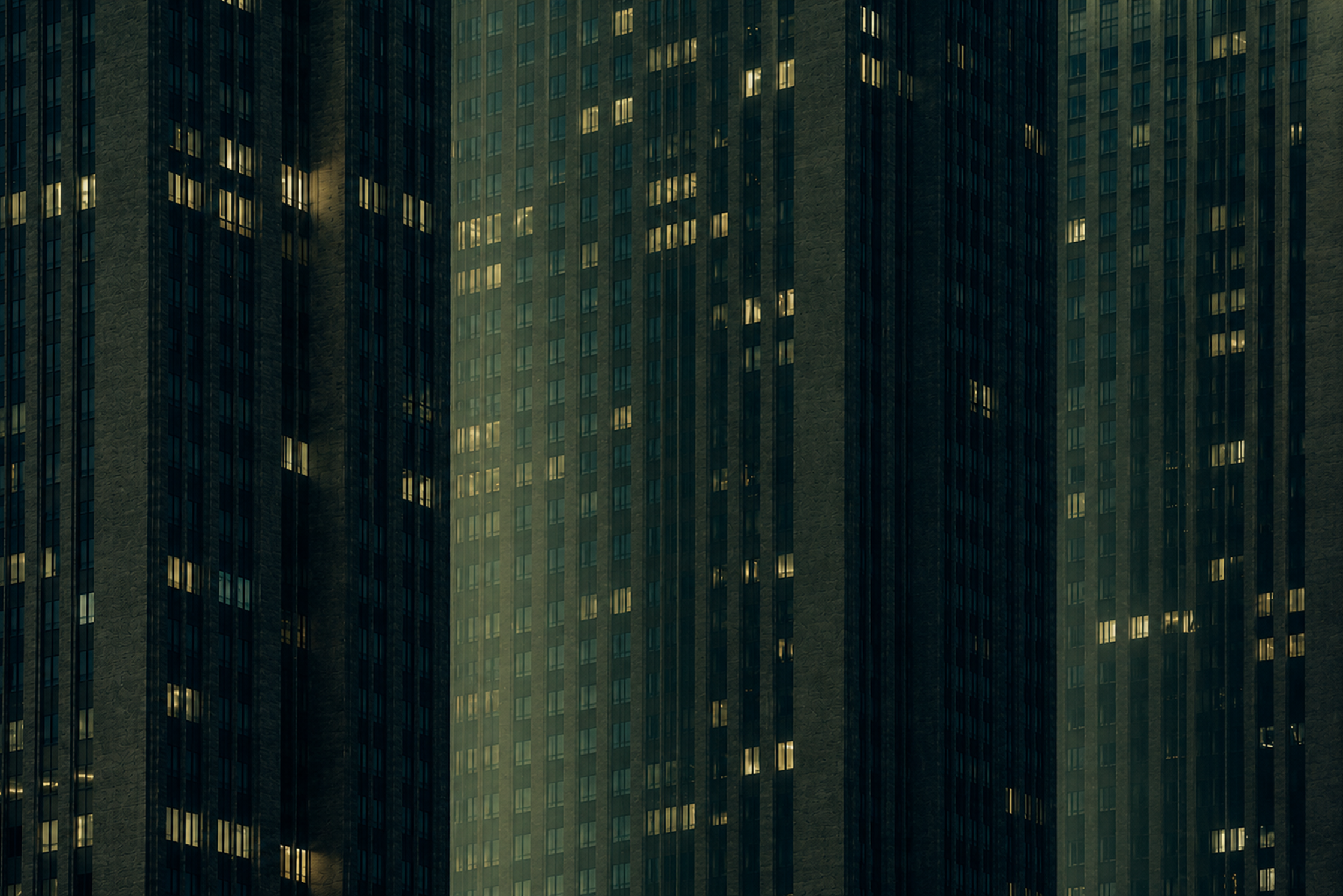 Nighttime high-rise apartment buildings with illuminated windows.